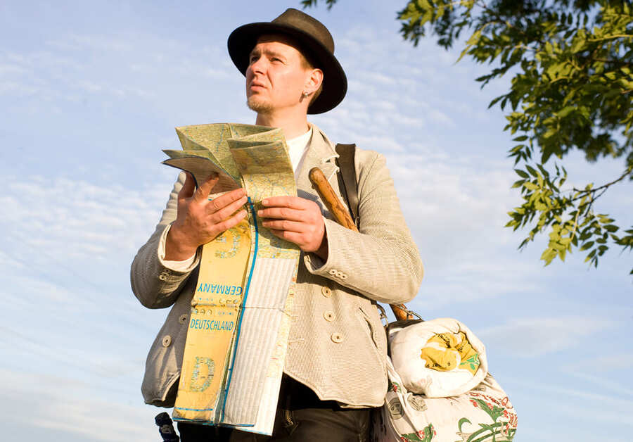 Männlicher Bäckergeselle in Traditionskleidung und Landkarte auf unter freiem Himmel